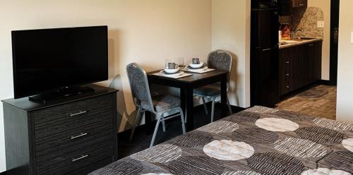 アトランタにあるSavannah Suites Atlanta Airportの小さなテーブル、ベッド2台、テレビが備わる客室です。
