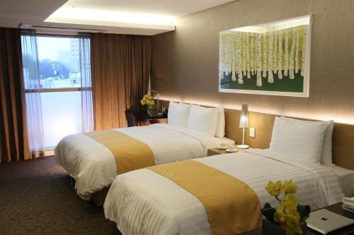 a hotel room with two beds and a window at Aventree Hotel Busan in Busan