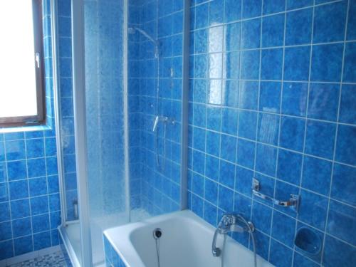 een blauw betegelde badkamer met een bad en een wastafel bij Gästehaus Stoanerhof in Unterwössen