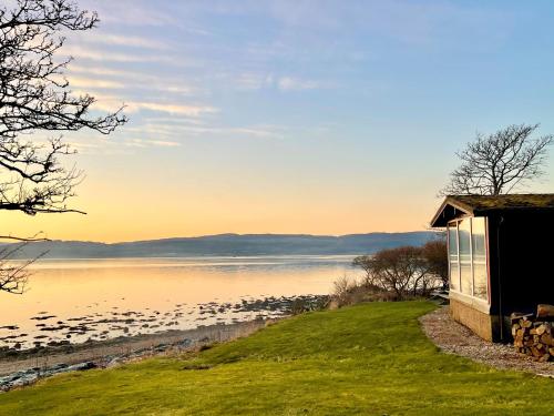 une maison sur la rive d'un lac avec des oiseaux dans l'établissement Oystershell Lodge, à Otter Ferry