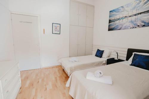 Habitación con 2 camas, paredes blancas y suelo de madera. en Pirgos beach house en Lárnaca