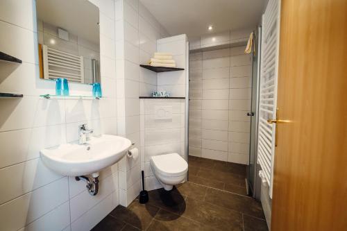 a white bathroom with a toilet and a sink at Hotel-Pension Hafemann in Senftenberg