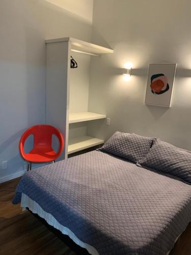 a bedroom with a bed and a red chair at Hotel Petit Village Icaraí in Niterói