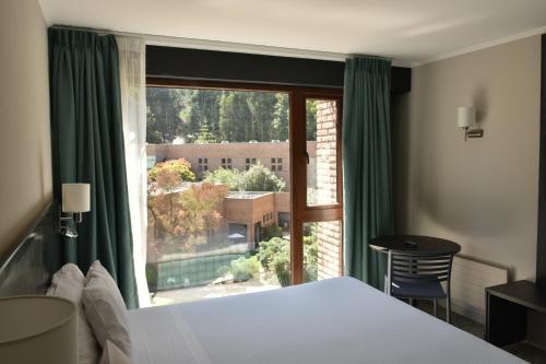 um quarto com uma cama e uma grande janela em Hotel Bosque de Reñaca em Viña del Mar