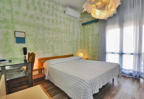 a bedroom with a bed and a desk and a window at Hotel Antonella in Caorle