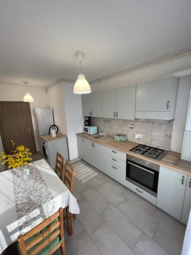 a kitchen with white cabinets and a table and a stove at Roxi's Apartment in Sibiu