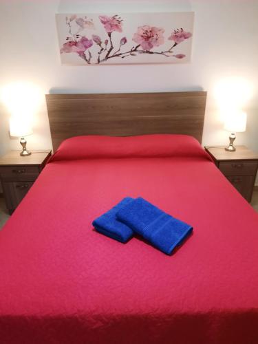 - un lit avec une couverture rouge et un oreiller bleu dans l'établissement Side Sea View Porto Paolo B, à San Pawl il-Baħar