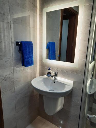 La salle de bains est pourvue d'un lavabo blanc et d'un miroir. dans l'établissement Side Sea View Porto Paolo B, à San Pawl il-Baħar