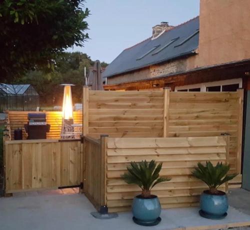 a wooden fence with two potted plants in front of a house at Le Breil Furet in Ménéac