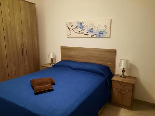 - une chambre avec un lit bleu et 2 tables de chevet dans l'établissement Side Sea View Porto Paolo C, à San Pawl il-Baħar