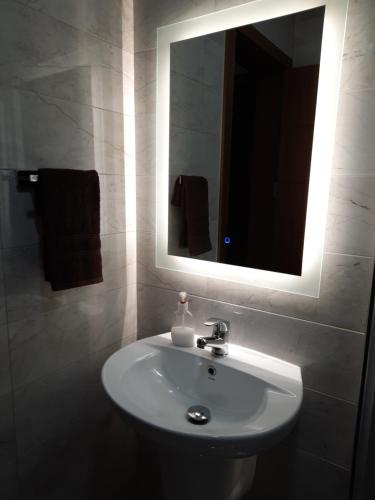 ein Badezimmer mit einem weißen Waschbecken und einem Spiegel in der Unterkunft Side Sea View Porto Paolo C in St Paul's Bay