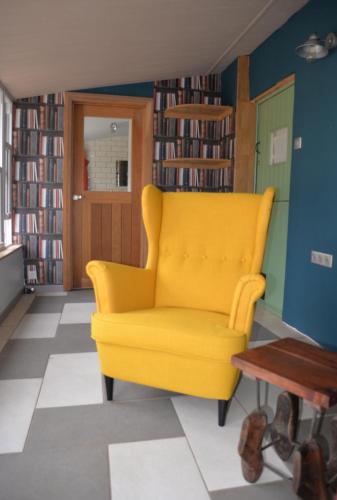 a yellow chair in a room with bookshelves at Le Breil Furet in Ménéac