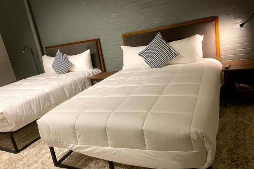 two beds in a room with white sheets and pillows at 3E-Spacious 2 bedroom in Oakland, sleeps 8 in Pittsburgh