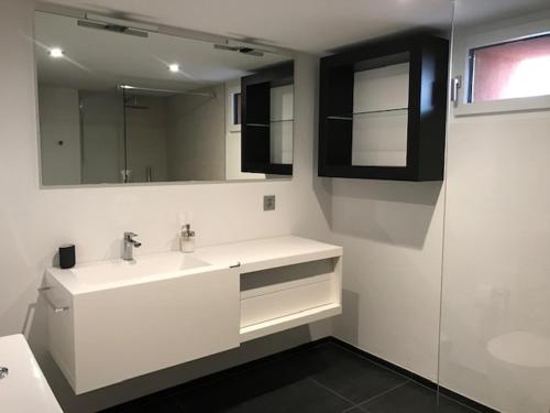 a white bathroom with a sink and a mirror at Blue River in Losone