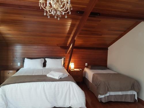a bedroom with two beds and a chandelier at Suite Tomaz Gonzaga in Ouro Preto