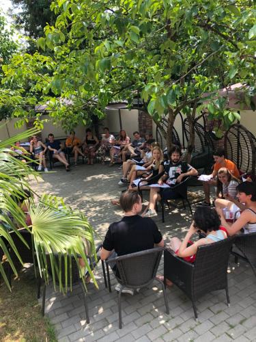 a group of people sitting in chairs under a tree at Hotel Homey Kobuleti in K'obulet'i