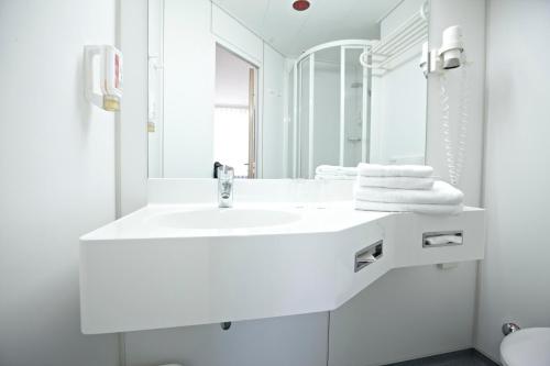 Baño blanco con lavabo y espejo en IntercityHotel Erfurt, en Erfurt