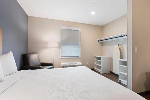 a bedroom with a white bed and a chair at Extended Stay America Premier Suites - Orlando - Sanford in Sanford