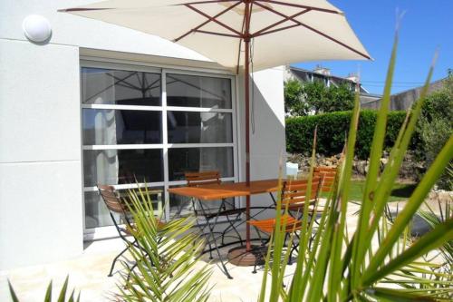 une table et des chaises avec un parasol sur une terrasse dans l'établissement MAISON DE VACANCES, A 150 m de la Mer, à Plouhinec