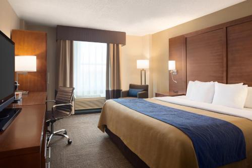 リトルロックにあるComfort Inn & Suites Presidentialの大型ベッドとテレビが備わるホテルルームです。