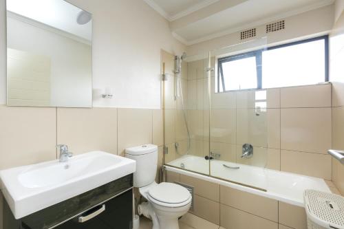 a bathroom with a sink and a toilet and a tub at Modern apartment in a secure golf estate.WIFI in Roodepoort