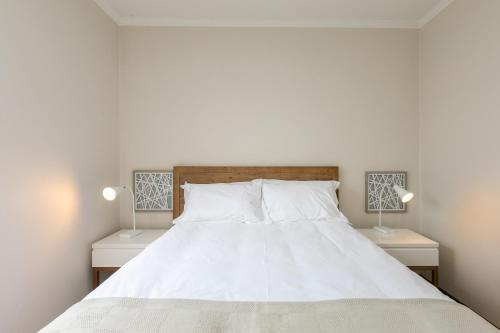 a bedroom with a large white bed with two lamps at Modern apartment in a secure golf estate.WIFI in Roodepoort