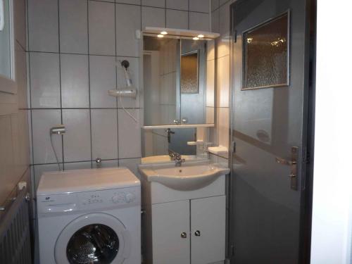 uma casa de banho com uma máquina de lavar roupa e um lavatório em La Maison Orange em Bully-les-Mines