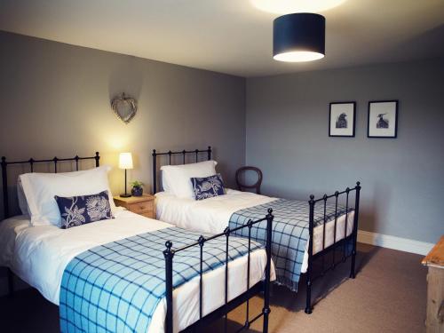 a bedroom with two beds with blue and white sheets at West House in Middleton in Teesdale