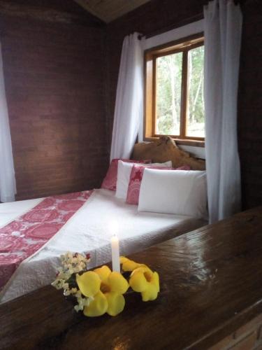 a candle sitting on top of a bed with flowers at RECANTO DO LEÃO in Aiuruoca