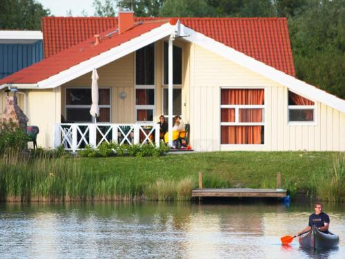 - un homme en kayak dans l'eau devant une maison dans l'établissement 12 person holiday home in Otterndorf, à Otterndorf