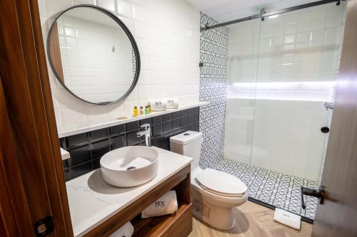 a bathroom with a sink and a toilet and a mirror at Six Hotel Guadalajara Degollado in Guadalajara