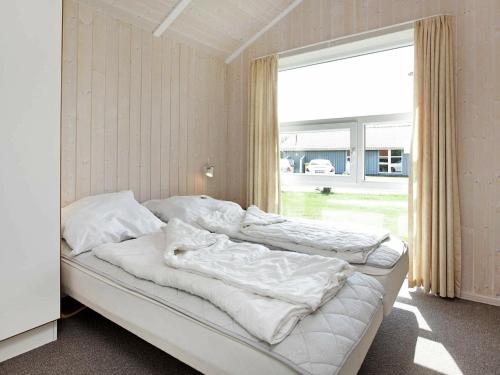 una camera con due letti con lenzuola bianche e una finestra di Four-Bedroom Holiday home in Otterndorf 13 a Otterndorf