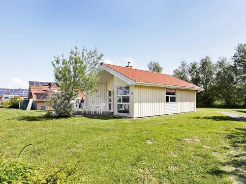 a small yellow house with a grass yard at 4 person holiday home in Otterndorf in Otterndorf