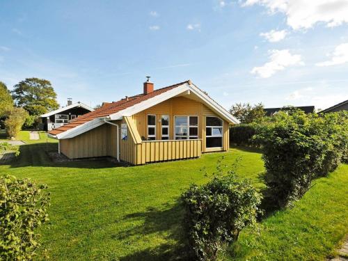 a small yellow house on a green lawn at 6 person holiday home in Gelting in Gelting