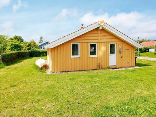 a small yellow house with a grass yard at 6 person holiday home in Gelting in Gelting