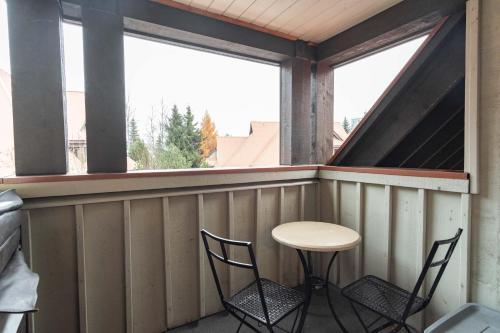 a porch with two chairs and a table and a window at Sunpath by Outpost Whistler in Whistler
