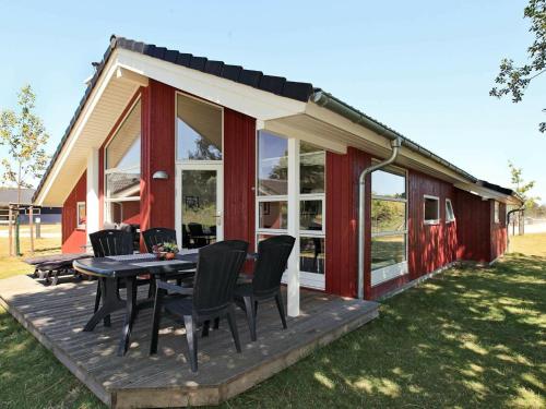 a red cabin with a table and chairs on a deck at 8 person holiday home in Gro enbrode in Großenbrode