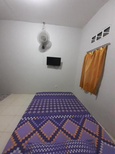 a bedroom with a bed with a purple blanket at Rumah Rahman Syari'ah in Bekasi