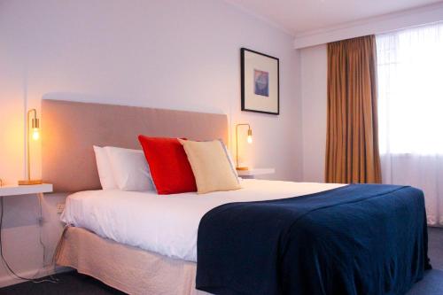 a hotel room with a large bed with red pillows at The Clan Terrigal in Terrigal
