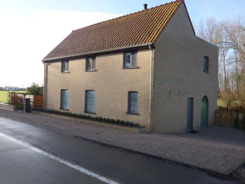 a brick house with a brown roof on a street at Charming Home with Garden in Zuienkerke