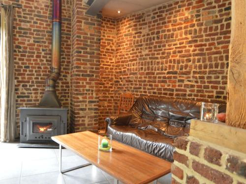 a living room with a leather couch and a brick wall at Spacious house in a farm located in the bucolic in Teuven