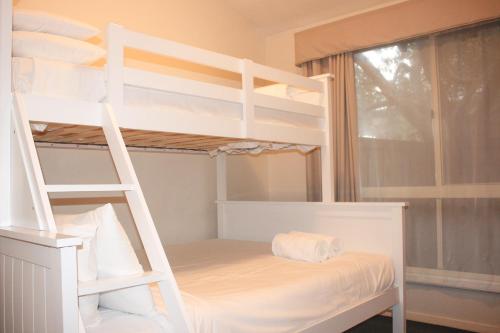 a white bunk bed with a ladder in a room at The Clan Terrigal in Terrigal