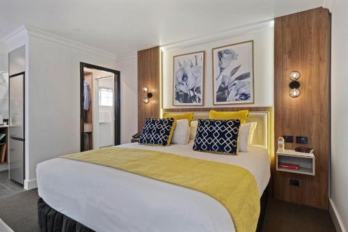 a bedroom with a large bed with yellow and blue pillows at Bluegum Dubbo in Dubbo