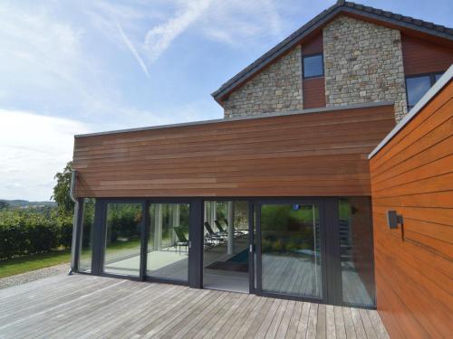 a house with glass doors on a wooden deck at Holiday Home in Malmedy with Indoor Heated Pool in Malmedy