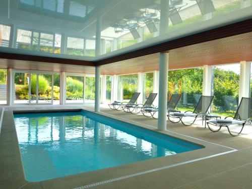 a swimming pool in a house with chairs and windows at Holiday Home in Malmedy with Indoor Heated Pool in Malmedy