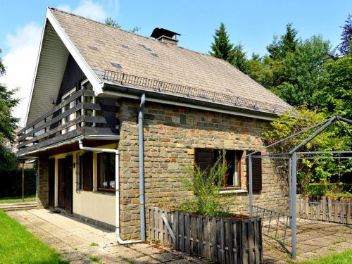 une vieille maison en briques avec une clôture devant elle dans l'établissement Inviting chalet in the woods in Ovifat, à Waimes