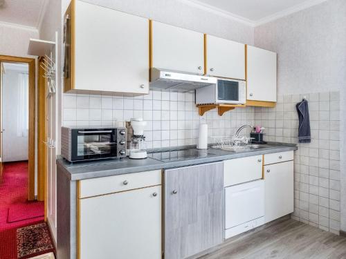 een keuken met witte kasten en een magnetron bij Ruhiges Apartment in Schwalefeld mit Garten in Willingen
