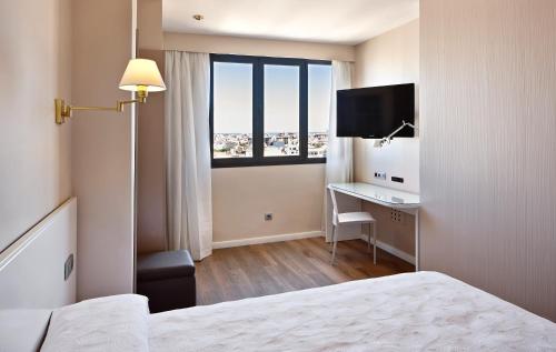 a hotel room with a bed and a desk and a window at Hotel Palladium in Palma de Mallorca