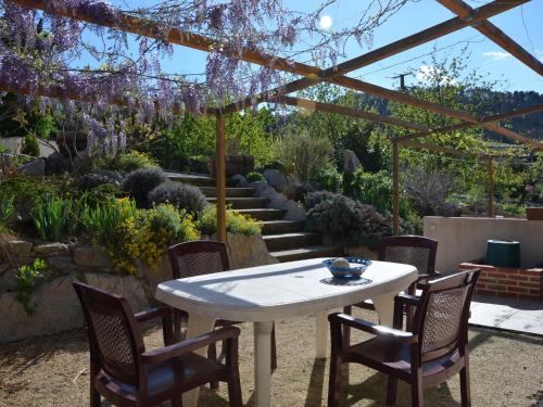 uma mesa e cadeiras num jardim com uma pérgola em Cottage around a swimming pool in a small villa em Courry