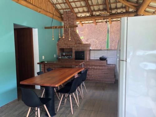 cocina con mesa de madera, sillas y nevera en Chalé Vista da Mata DM, 5km Centro Domingos Martins, Wi Fi, fibra óptica, SPA aquecido, split, privacidade, aceita pets, en Domingos Martins